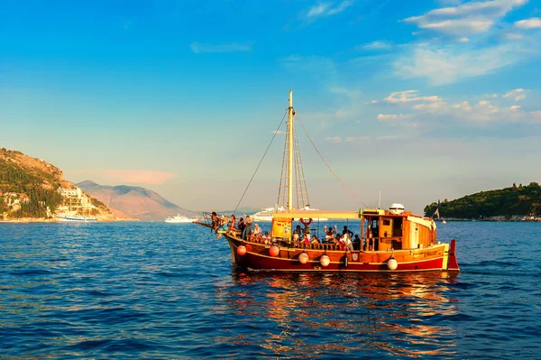 Tourists riding in an old ship in the Adriatic sea near Dubrovnik at sunset