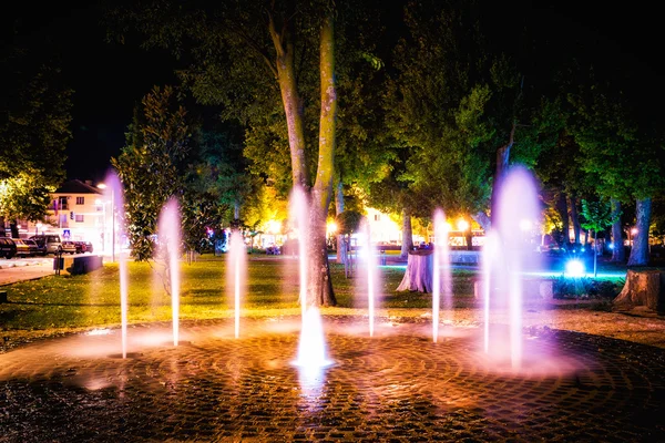 Small fountain in the city park on a summer night