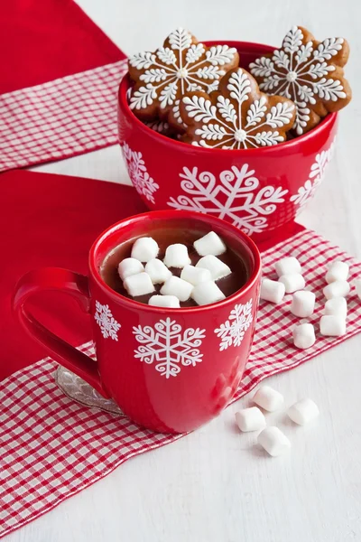 Red mugs with hot chocolate and marshmallows and gingerbread cookies