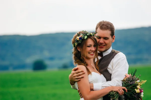 Portrait of the bride and groom with a bouquet on the green field