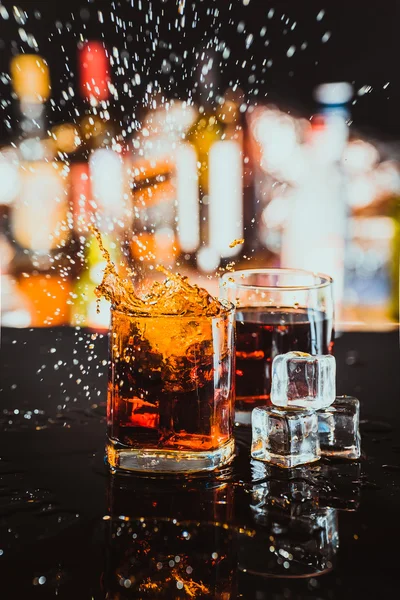 Two glasses of whiskey on a blurred background bar