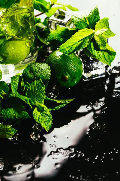 Glass of mojito with lime and mint ice cube close-up red straw on dark background