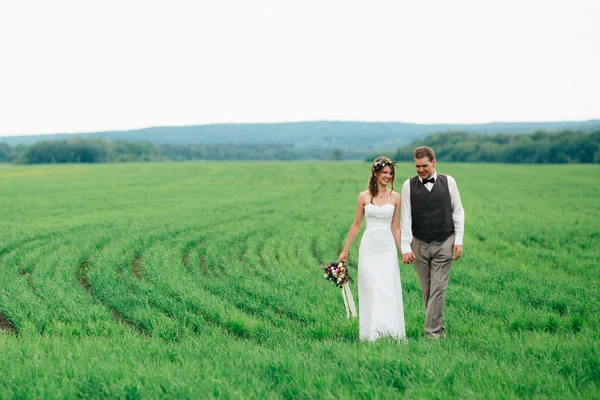 The bride and groom with a bouquet on the green field
