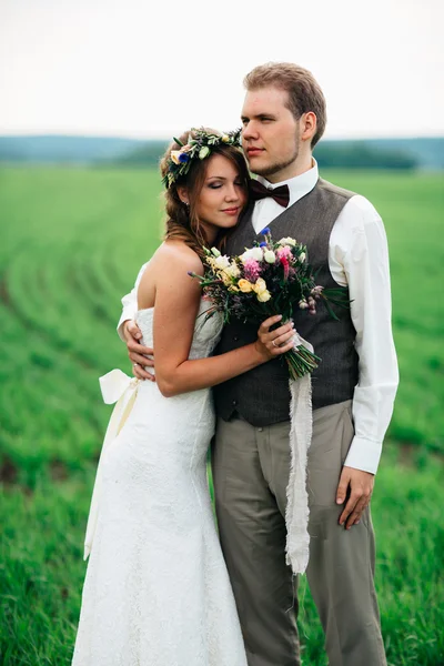 The bride and groom with a bouquet on the green field