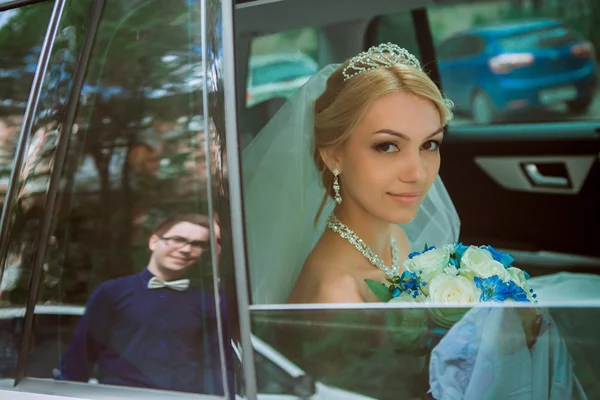 Close-up portrait of a pretty shy bride in a car window