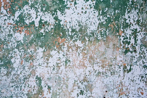 Grunge wall texture background. Paint cracking off dark wall with rust underneath.