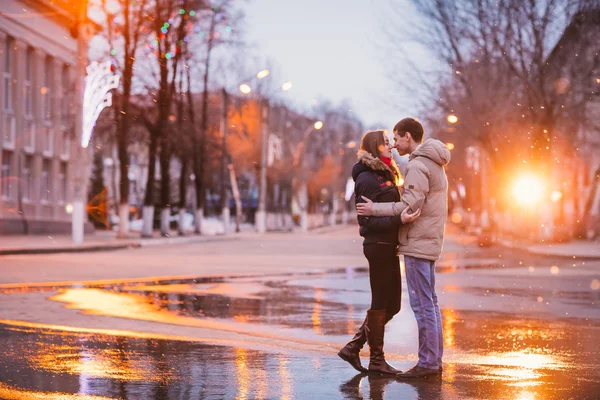 Portrait of young beautiful couple kissing in an autumn rainy day.
