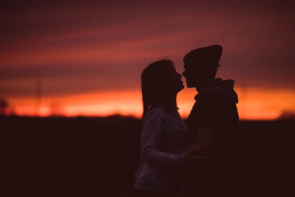 Silhouettes of hugging couple against the sunset sky. Vintage photo.