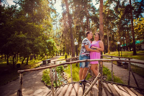 Romantic young couple kissing  and stand to bridge on background summer forest