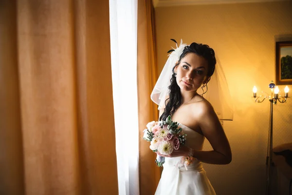 l young happy bride standing near the window -
