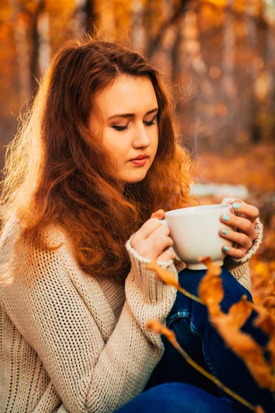 Girl with cup tea on a background of autumn forest