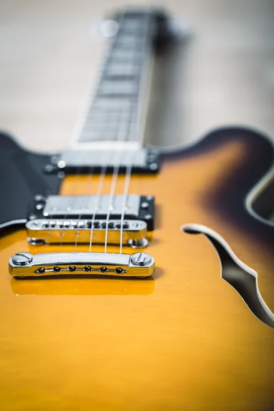 Electric jazz guitar close up on an orange sunburst color and chrome electronics