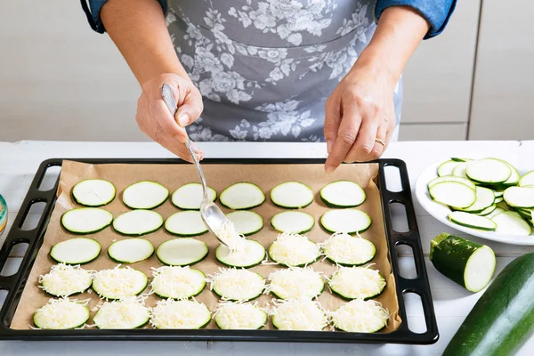 Preparing zucchini with cheese to bake