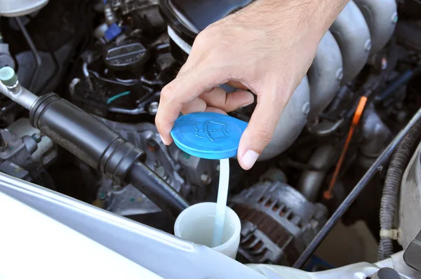 Hand opening car windscreen washer tank checking water level