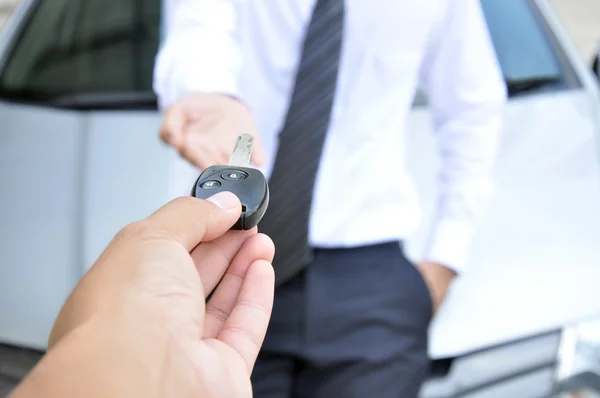 Hand giving a car key to another man