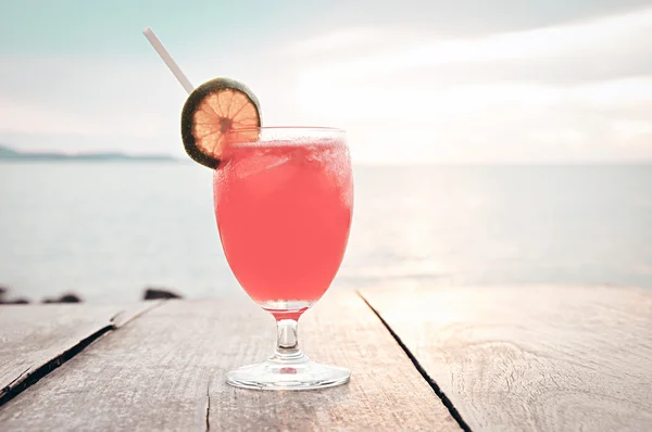 Cocktail drink on wooden table with sea & sky background