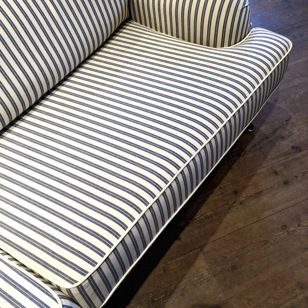 Elegant striped sofa on dark wooden floor