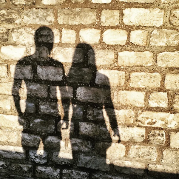 Shadows of man and woman on a brick wall