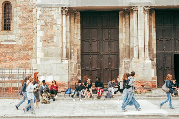Some young people enjoying a sunny day, sitting on a stone near church of St. Sernin