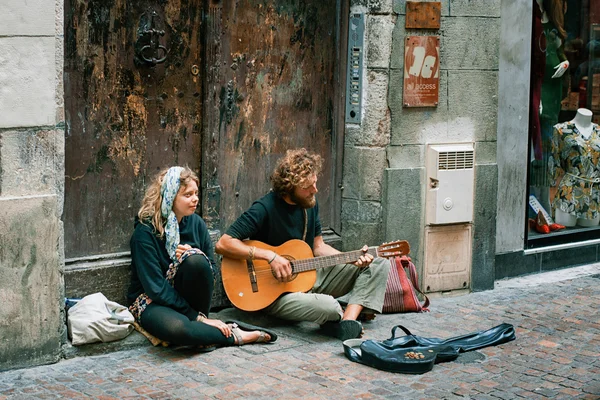 Young man and woman are making money playing guitar on the street in the city of Toulouse