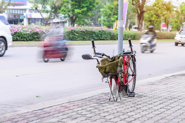 Broken bicycle locked with pillar in city.