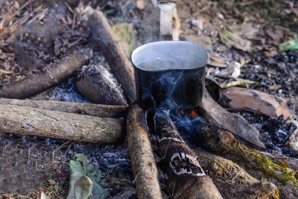 Boiling water using bonfire on vacation at campsite.