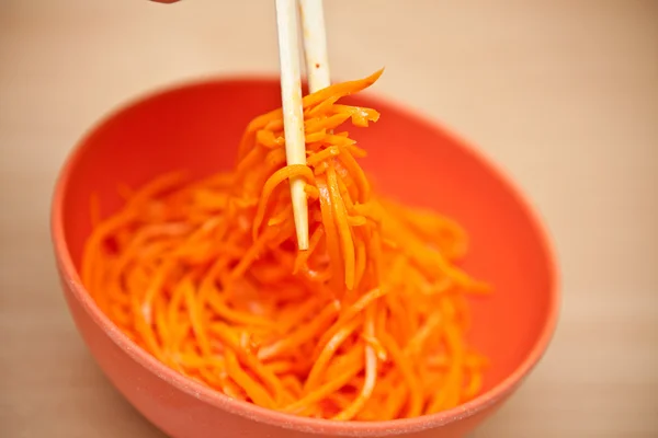 Korean carrots on a plate next to chopsticks