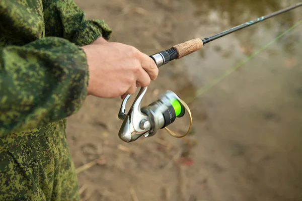 Spool of fishing line on a spinning in the hands of a fisherman,