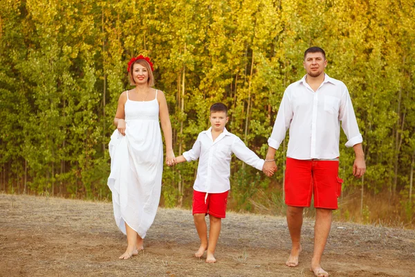 Mom Dad and son walking through the woods hand in hand