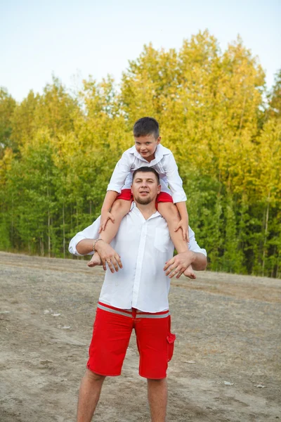 His son on the shoulders of his father for a walk in the park