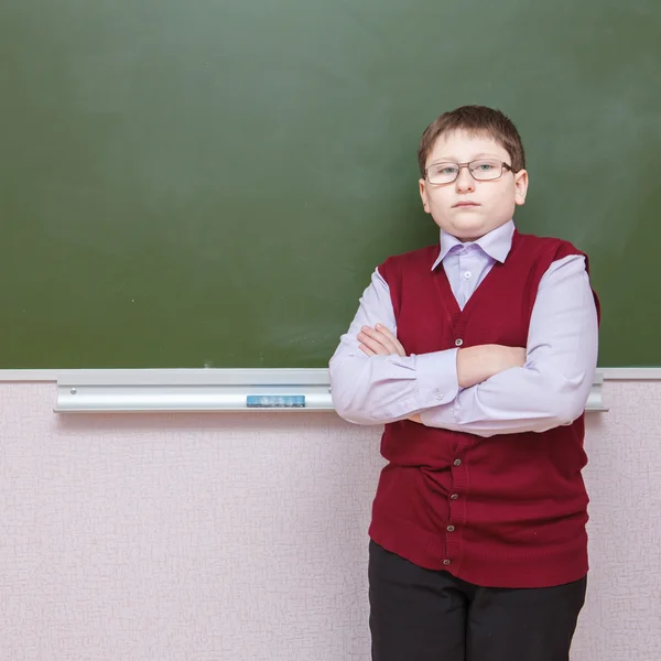 Boy standing with his arms crossed at a school board