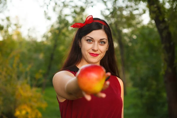 Beautiful woman posing with an apple in the park