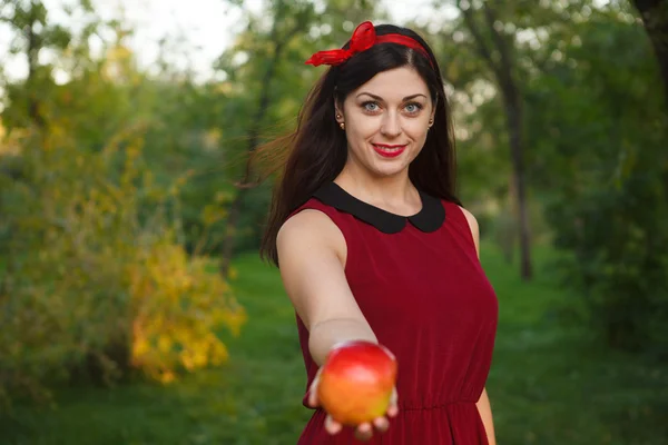 Beautiful woman posing with an apple in the park