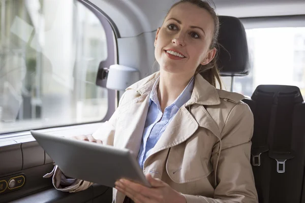 Successful businesswoman in car with tablet