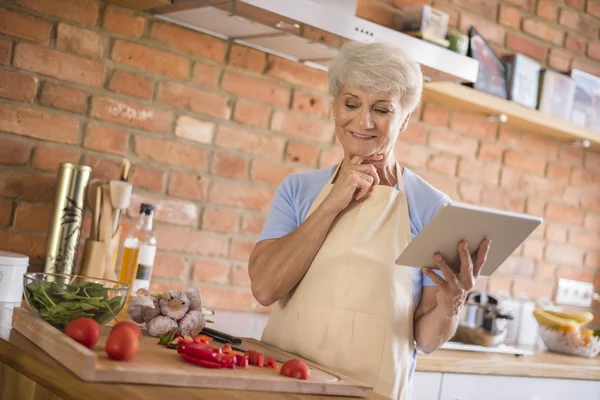 Mature woman looking recipe on tablet