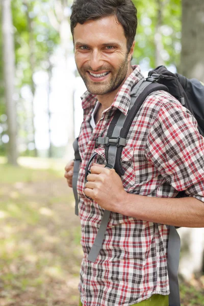 Smiling man hiking in forest
