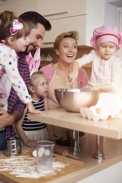 Parents teach girls how to bake a cake