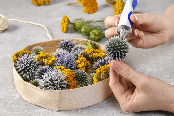 Florist make floral decoration with wild plants in round box