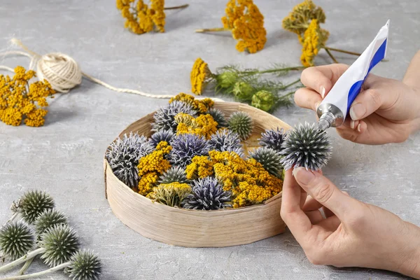 Florist make floral decoration with wild plants in round box