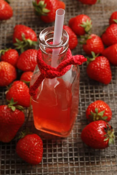 Bottle of strawberry juice and ripe raw strawberries