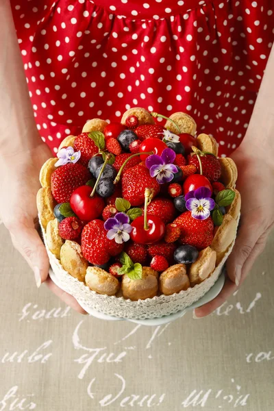 Woman holding summer sponge cake with fruits