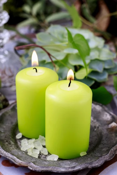 Green scented candles on silver plate.