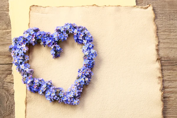 Heart shaped wreath made of forget-me-not flowers. Vintage sheet
