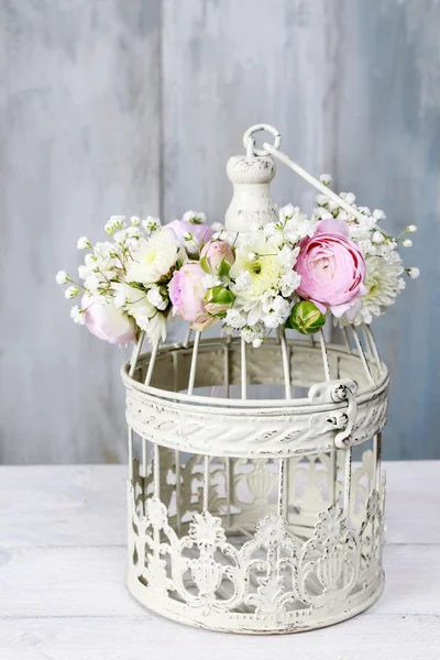 Vintage bird cage decorated with wreath made of pink ranunculus