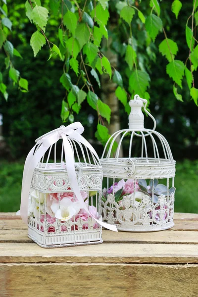 Garden party decorations. Vintage bird cages with flowers inside