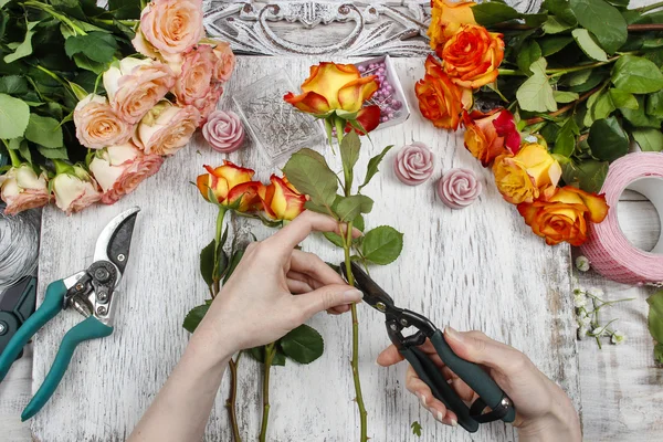 Florist at work. Woman making wedding bouquet of orange roses