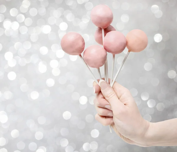 Woman holding a few pink cake pops in hand