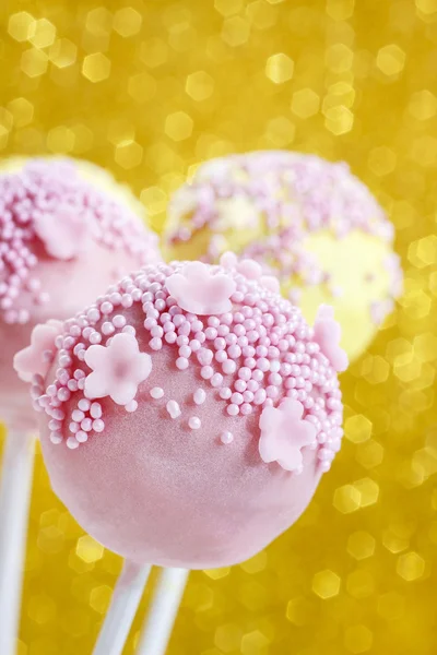Pink and yellow cake pops decorated with sprinkles.