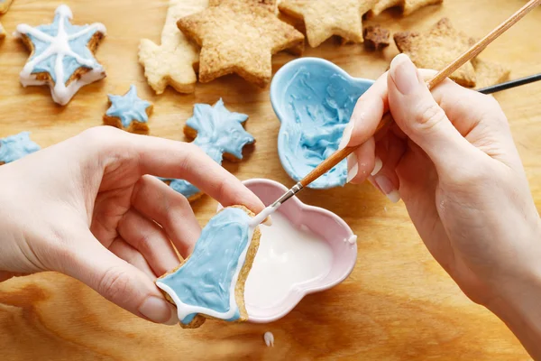 Decorating gingerbread cookies with blue and white icing.