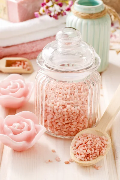 Glass jar of pink sea salt on white wooden table